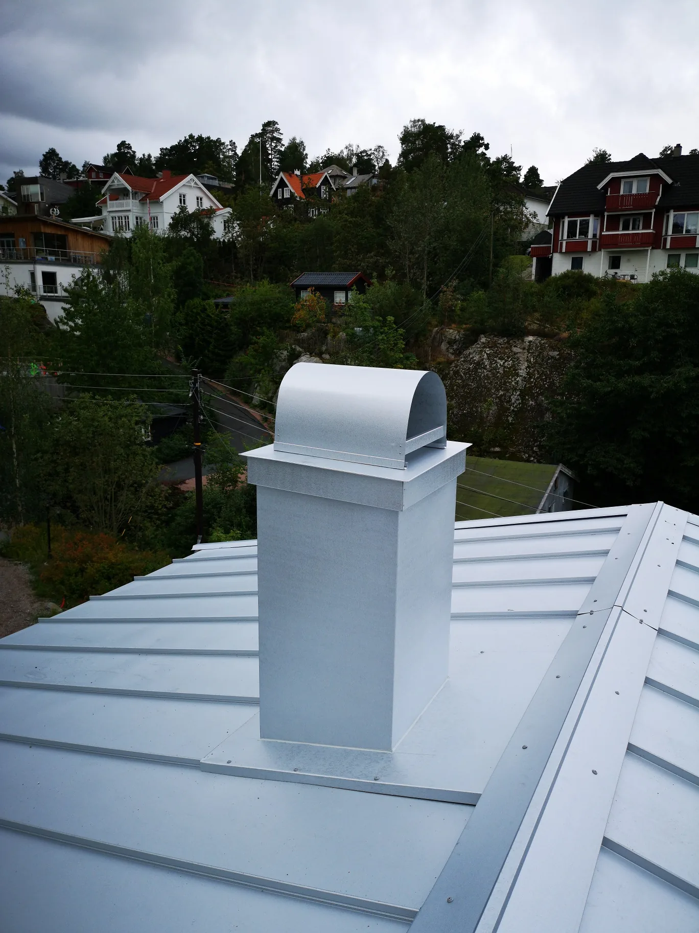 Sølvfarget pipebeslag med buet hatt på båndtekket tak på Nesodden